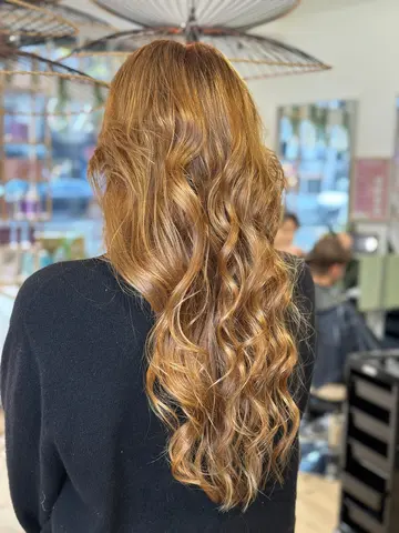 Coloration blond cuivré doré sur cheveux longs bouclés